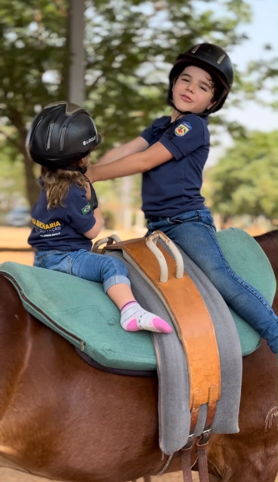 Duas crianças de uniforme Rancharia montando o mesmo cavalo